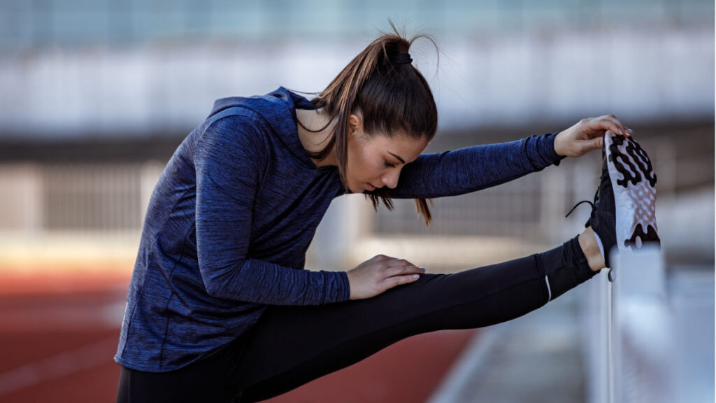 Young woman stretching her hamstring at a track.
